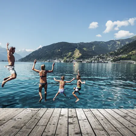 Eltern springen zusammen mit zwei Kindern in den Zellersee bei Sonnenschein