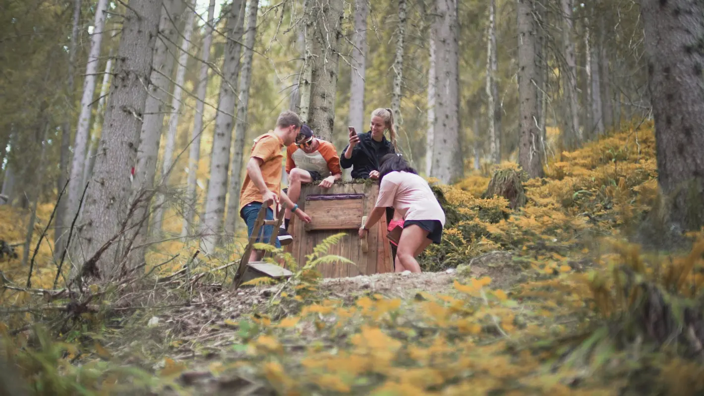 Vier junge Leute untersuchen eine Holztür im Wald