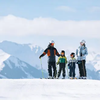 Familie mit zwei Kindern beim Skifahren im Skicircus Saalbach Hinterglemm Leogang Fieberbrunn vor Bergpanorama