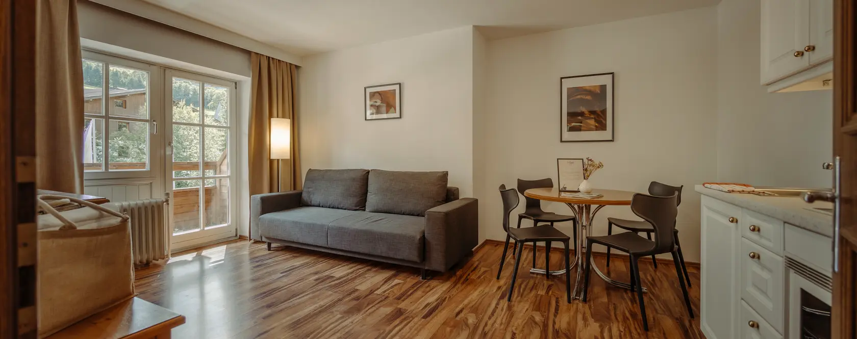 Wohnzimmer mit grauer Couch, Esstisch und Holzboden