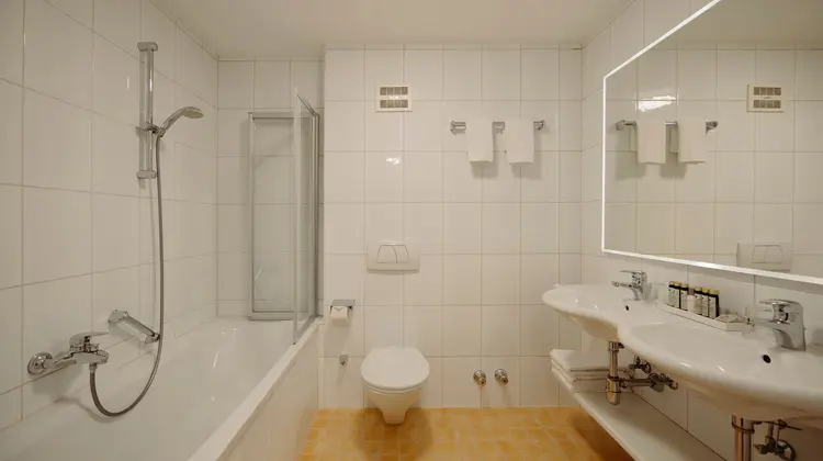 Bright bathroom with bathtub, shower, toilet and sink