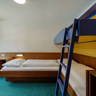Zimmer mit Einzelbett und blauem Hochbett mit Leiter