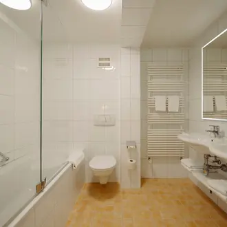 Helles Badezimmer mit Dusche, Toilette, Waschbecken und Handtuchwärmer