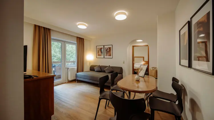 Living room with sofa, dining table, chairs and window to the balcony