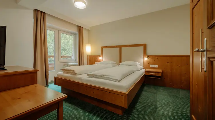 Hotel room with double bed, window and green carpet