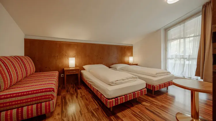 Zwei Betten und ein Sofa in einem Zimmer mit Holzboden und Nachttischen