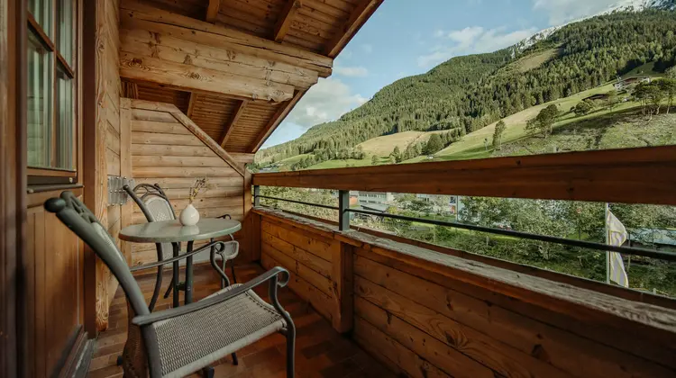 Holzbalkon mit Tisch und Stühlen vor Berglandschaft