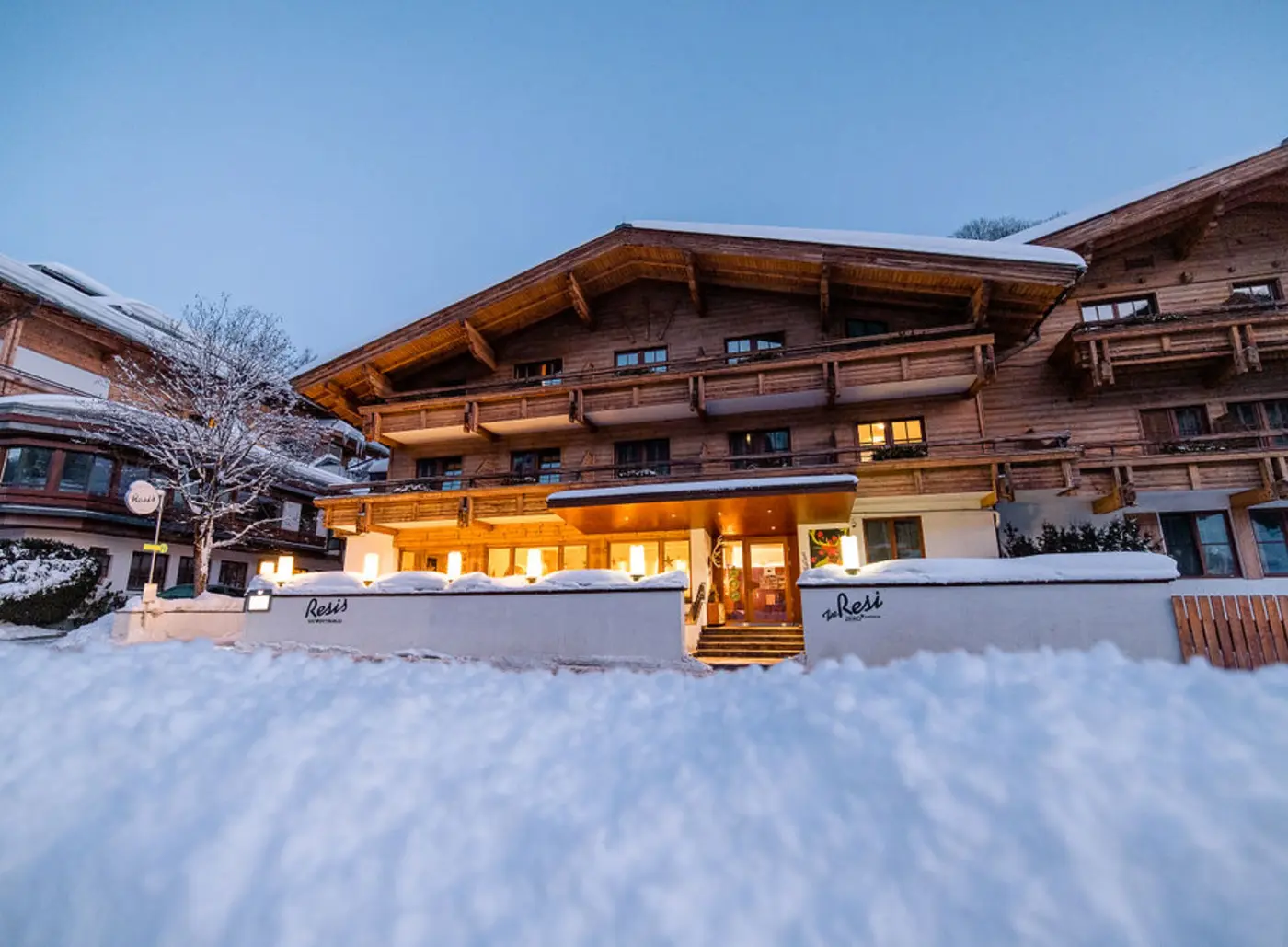 Außenansicht des Gartenhotel Theresia im Winter mit Schnee und beleuchteten Fenstern
