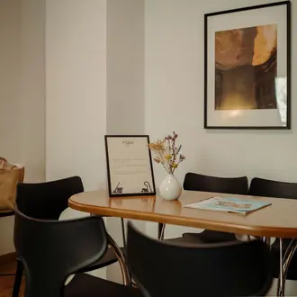 Tisch mit Blumen, Speisekarte und Broschüre in hellem Raum mit Gemälde