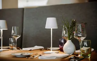 Tisch mit Gedeck, Lampe und Blumenvase