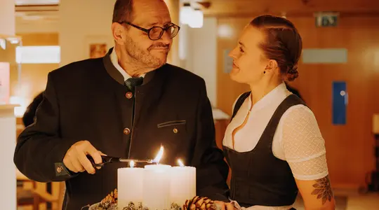 Mann zündet Adventskranz an, Frau schaut zu