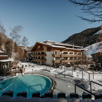 Beheizter Außenpool des Gartenhotel Theresia mit Dampf und Schnee vor Bergkulisse