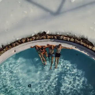 Vier Personen liegen im Pool, umgeben von Schnee