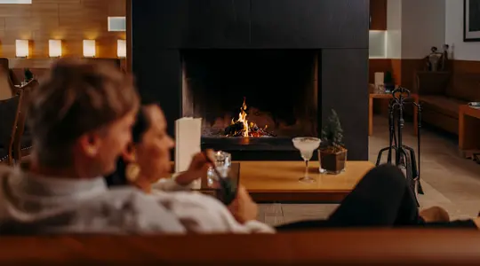 Paar vor Kamin mit Cocktailgläsern auf Tisch