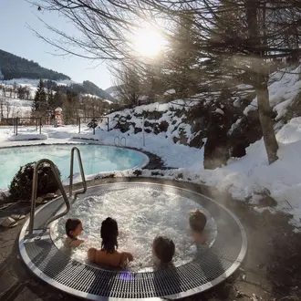 Winter landscape with steaming whirlpool and outdoor swimming pool