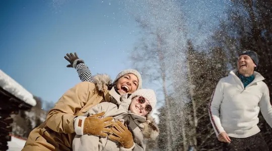 Frau und Kind im Schnee, lachend, mit Mützen und Winterkleidung, Schneeballwurf
