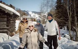 Familie mit Winterkleidung und Sonnenbrillen im Schnee vor Bergkulisse