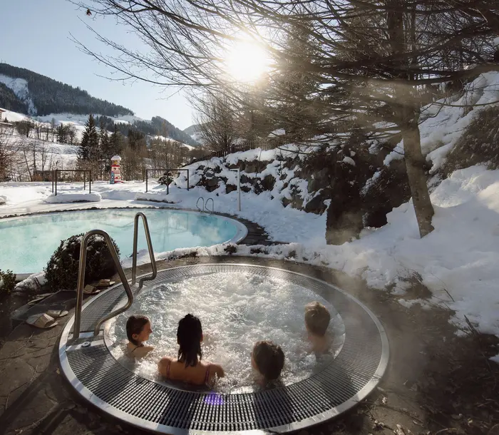 Winterlandschaft mit dampfendem Whirlpool und Badenden im Vordergrund
