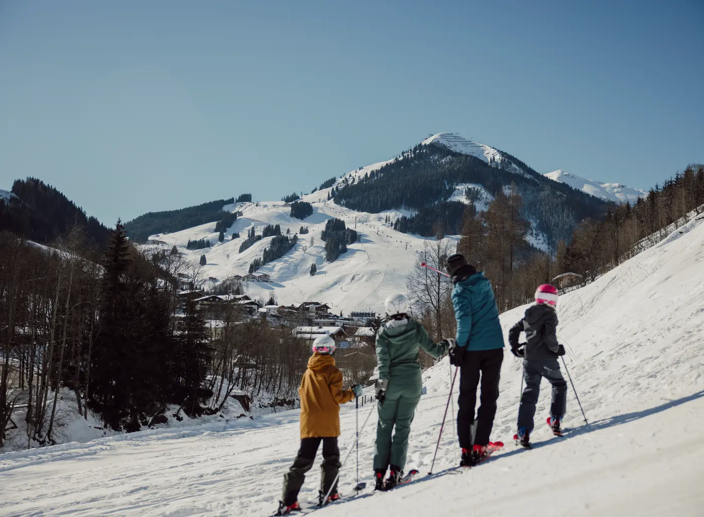 Familie beim Skifahren auf schneebedeckter Piste mit Bergpanorama im Hintergrund