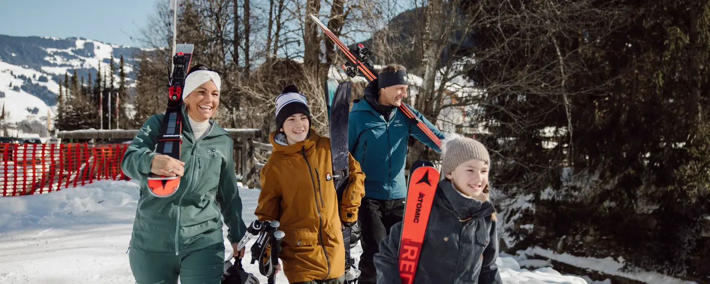 Familie mit Skiern und Skischuhen geht durch verschneite Winterlandschaft