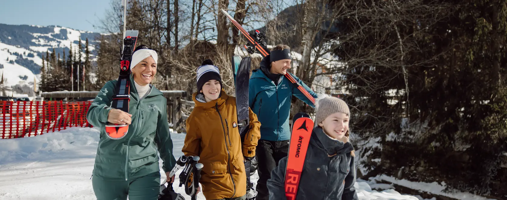 Familie mit Skiern und Skischuhen geht durch verschneite Winterlandschaft
