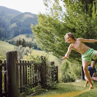 Vater mit Sohn beim Slacklinen im Garten