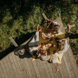 Eltern mit Kinder beim Picknicken auf der Holzterrasse im Wald