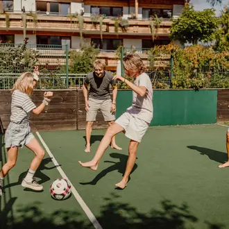 Eltern spielen mit Kindern im Fußballkäfig
