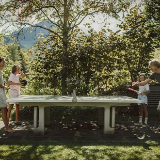 Eltern spielen Tischtennis mit ihren zwei Kindern
