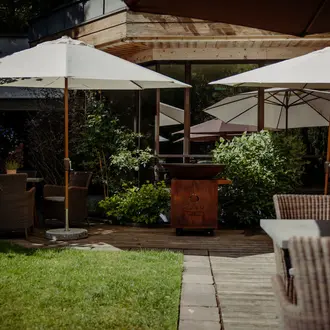 Außenbereich eines Restaurants mit Sonnenschirmen, Tischen, Stühlen und Grünpflanzen