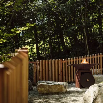 Feuerstelle im Garten mit Holzzaun und Steinen