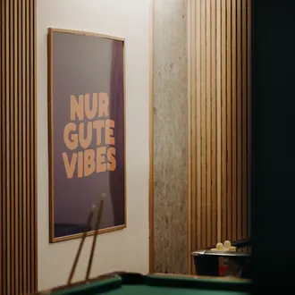 Poster mit Aufschrift "Nur gute Vibes" in einem Raum mit Billardtisch und Holzvertäfelung