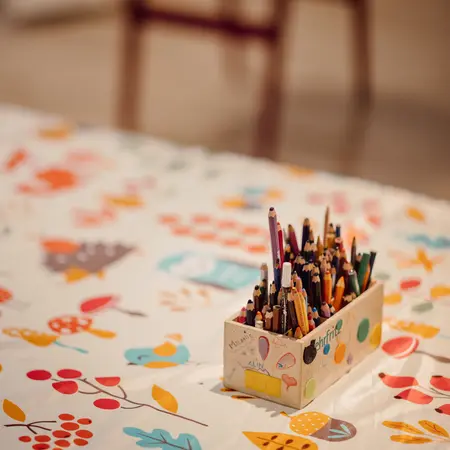 Stifte in einer Box auf einer Tischdecke mit Herbstmotiven