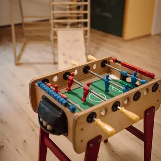 Tischfußballspiel aus Holz mit roten und blauen Figuren auf einem Holzboden