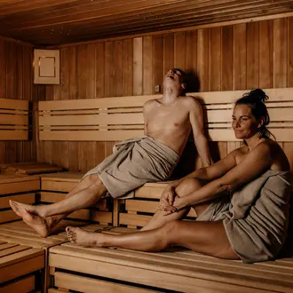 Mann und Frau entspannen in Handtücher gehüllt in einer Sauna