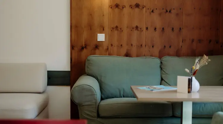Wohnzimmer mit grüner Couch, Holzwand und Lampe