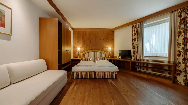Hotelzimmer mit Doppelbett, Holzvertäfelung und Sofa