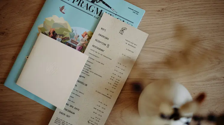 Zeitschrift, Karte und Rechnung liegen auf einem Holztisch