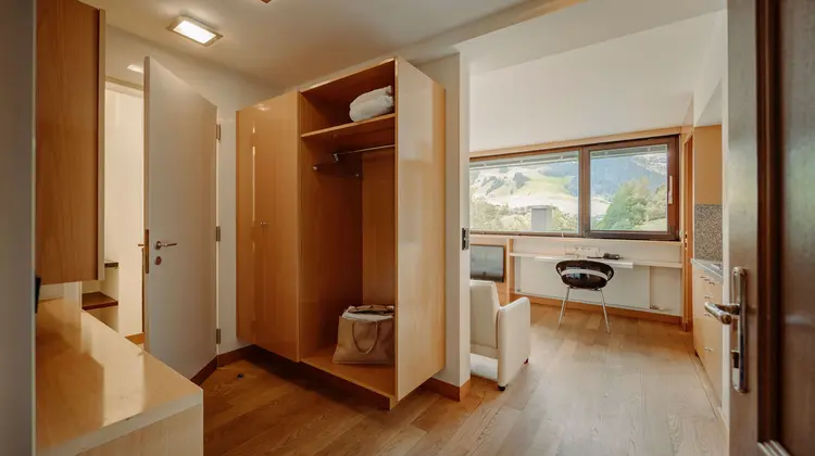 Heller Flur mit Holzschrank, Holzboden und Blick in ein Zimmer mit Schreibtisch und Fenster