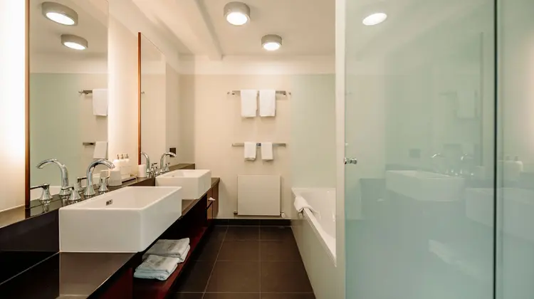 Helles Badezimmer mit zwei Waschbecken, Badewanne und Handtüchern