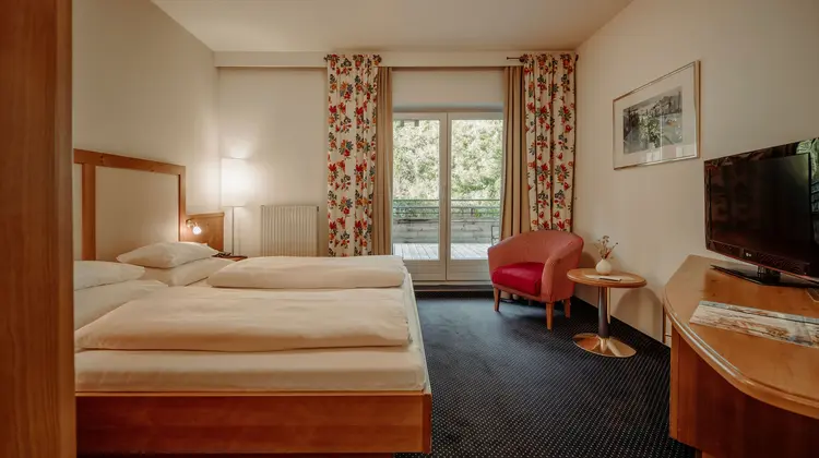 Hotelzimmer mit Doppelbett, Sessel und Balkon