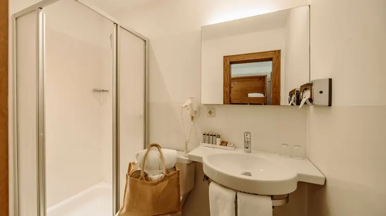 Helles Badezimmer mit Dusche, Waschbecken, Spiegel und Handtasche auf der Toilette