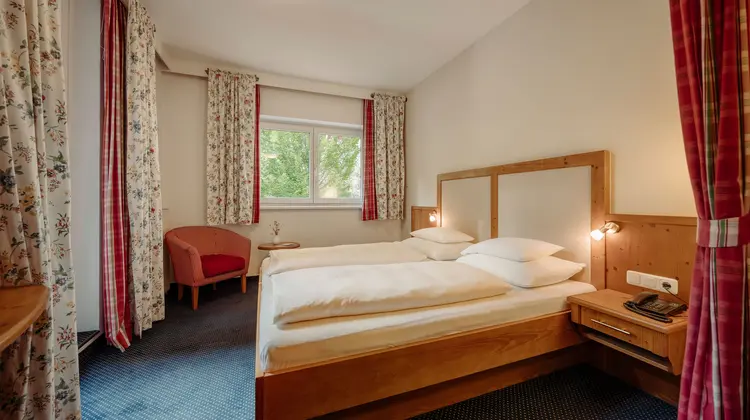 Hotelzimmer mit Doppelbett, Fenster und Sessel