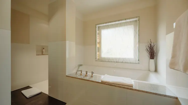 Helles Badezimmer mit Fenster über Badewanne und Dekoration