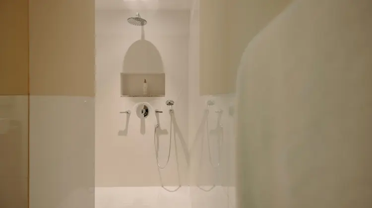 Weisse Dusche mit Armaturen und Duschkopf